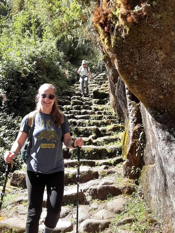 Hiker with trekking poles on stone steps of the Inca Trail